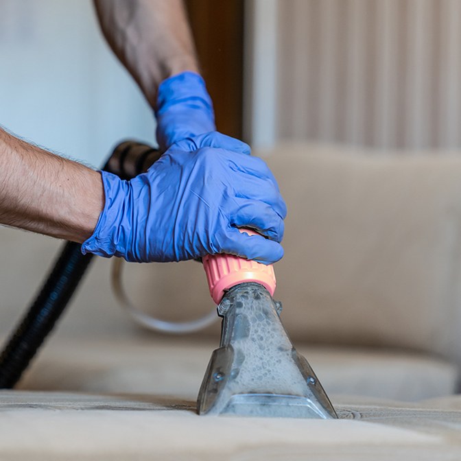 Steritec technician deep-cleaning upholstery on a couch with a steam extraction tool